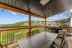 Una terraza al aire libre con una parrilla, asientos y vistas a una zona residencial.