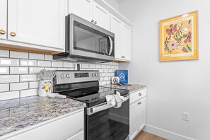 A kitchen with white cabinets, a stainless steel microwave, a stove, and a tiled backsplash. - Breathtaking Lakeview Retreat with Private Hot Tub, Dog-Friendly, Cmty Pools & $400 Free Tickets (Branson)