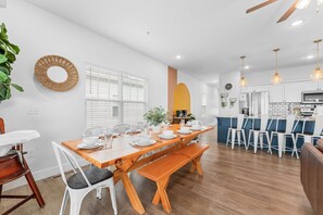 A modern kitchen with white cabinets, a built-in oven, and a dining area with a wooden table and benches.