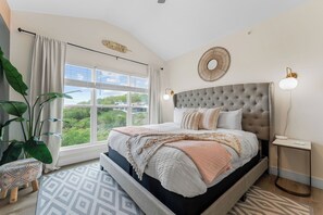 Un dormitorio con una cama grande, vistas a zonas verdes y una decoración circular en la pared.