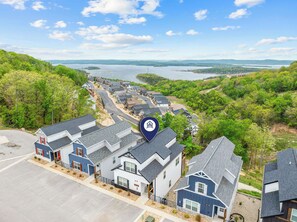 Un barrio residencial con casas, una carretera y un lago al fondo.