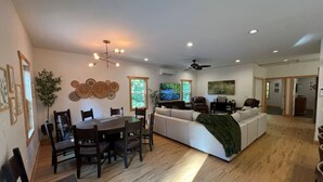 Un salon spacieux avec un grand canapé, un coin repas comprenant une table et des chaises en bois, et un ventilateur de plafond.