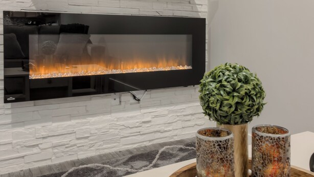 A modern living room with a fireplace, a television mounted on the wall, and a decorative tray with candles and a plant. - Fully Reno'd 2 Bedroom, 2 Bath Legal Basement Suite. Heart of the Southside (Lethbridge)