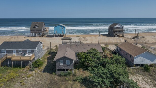A coastal area with multiple houses, some elevated on stilts, near the beach. - 7041- Duck Dog - Rodanthe Beach Cottage | Ocean Views (Rodanthe)