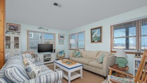 A living room with a sofa, armchair, coffee table, television, and decorative items. - 7041- Duck Dog - Rodanthe Beach Cottage | Ocean Views (Rodanthe)