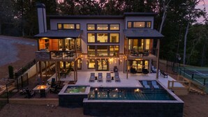 A modern two-story house with a large outdoor pool, multiple seating areas, and a tennis court. - Retreat at Clear Creek ~ Outdoor Pool & Pickleball/Basketball Court! (Ellijay)