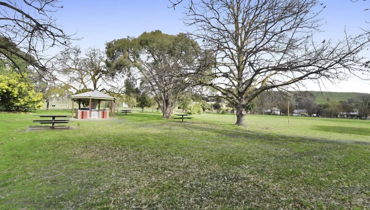 A park with picnic tables, a gazebo, and trees.