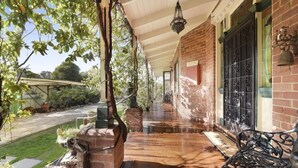 A covered porch with a brick wall, a metal gate, and a hanging lantern.