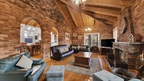 A rustic living room with exposed brick walls, a leather sofa, a wooden coffee table, and a fireplace.