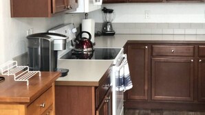 A kitchen with wooden cabinets, a microwave, a kettle, and a coffee maker. - Nightly or short term rental in Medford. (Medford)