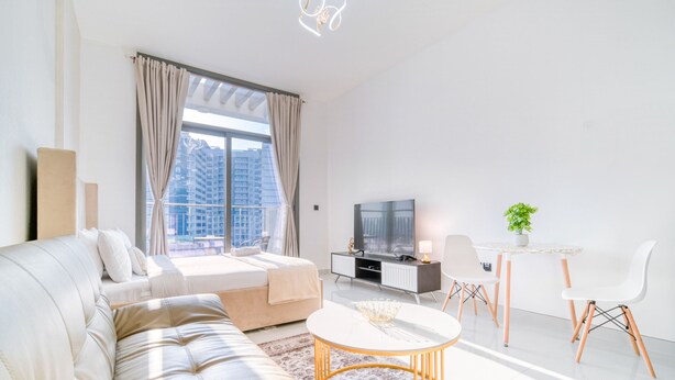 Un salon moderne comprenant un canapé, une table basse, un téléviseur et un coin repas avec des chaises et une table.