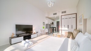 Une chambre d’hôtel moderne dotée d’un grand lit, d’un téléviseur à écran plat, d’un coin repas et d’une kitchenette.