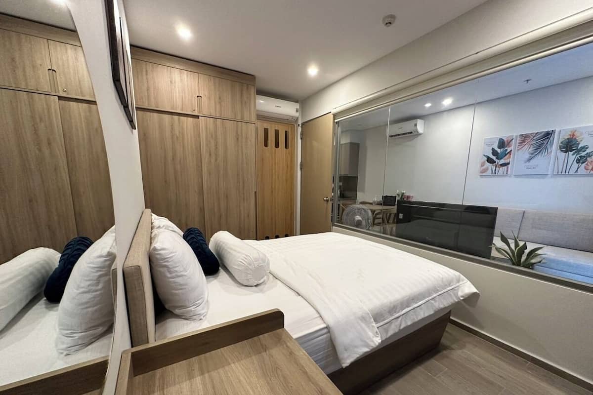 A modern bedroom with a bed, wooden wardrobe, and a large mirror.