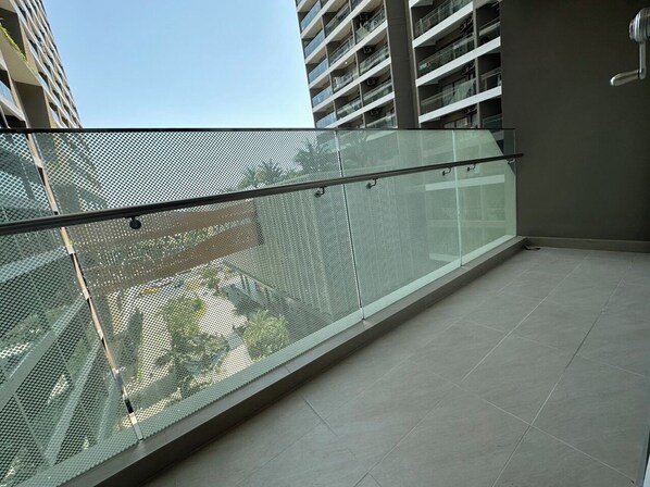 A balcony with a glass railing, a tiled floor, and a view of a high-rise building in the background. - Bin's House in The Song Vung Tau (Ho Chi Minh City)