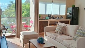 Ein modernes Wohnzimmer mit einer Couch, einem Couchtisch und einem Balkon mit roten Stühlen.