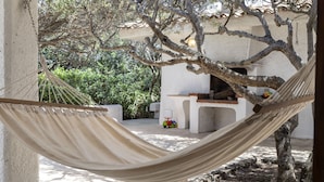 A hammock hanging between two columns in a courtyard with a stone wall, a small table, and a toy car. - Vacation home Giulia by Interhome (Portobello)