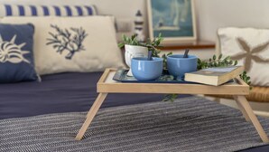 A cozy living room with a sofa, decorative pillows, a small table with blue bowls and a book, and a framed picture on the wall. - Vacation home Giulia by Interhome (Portobello)