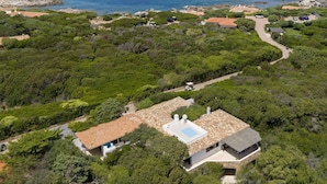 A coastal property with a central building surrounded by lush greenery, a paved driveway, and a view of the sea. - Vacation home Giulia by Interhome (Portobello)