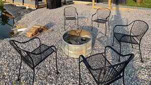 A modern building with a gravel patio, outdoor seating, and a fire pit.
