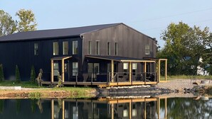 A modern building with a large deck and a reflection in the water.