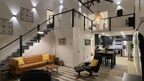 A spacious living area with a staircase leading to a second floor, a dining area, and a kitchen.