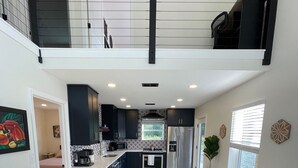A modern kitchen with dark cabinets, a central island, and a dining area with a wooden table and four chairs.