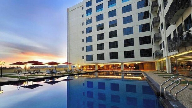 Un hotel moderno con piscina, tumbonas y sombrillas.