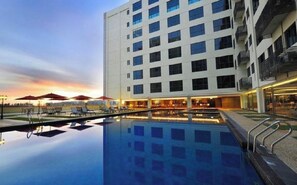 Un hotel moderno con piscina, tumbonas y sombrillas.
