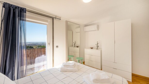 A bedroom with a bed, a wardrobe, a mirror, and a view of the outdoors. - One haven with stunning views (Alcabideche)
