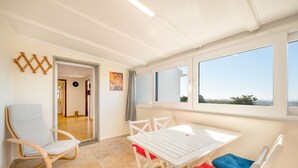 A bright room with a white table and chairs, a large window with a view, and a door leading to another room. - One haven with stunning views (Alcabideche)