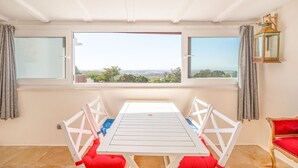 A room with a white table and chairs, large windows, and a view of the city. - One haven with stunning views (Alcabideche)