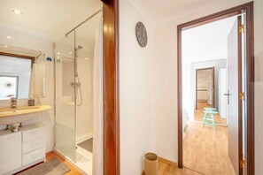 Une salle de bain moderne avec une douche à parois de verre, un meuble-lavabo en bois et un miroir.
