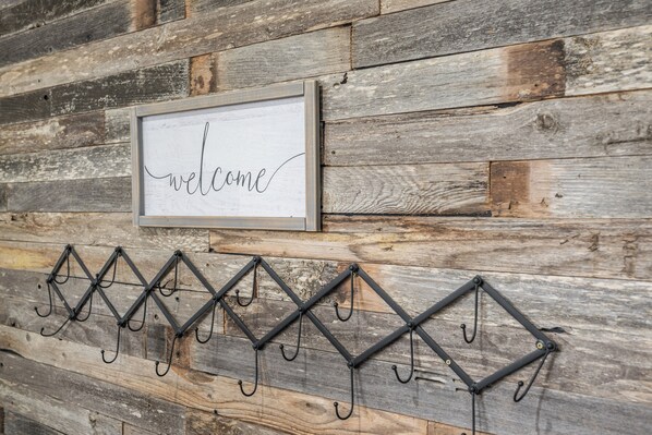 A rustic wooden wall with a welcome sign and a metal rack with hooks. - Welcoming Guest Suite in Snohomish (Snohomish)