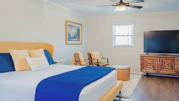 A bedroom with a bed, a television, a ceiling fan, and a window.