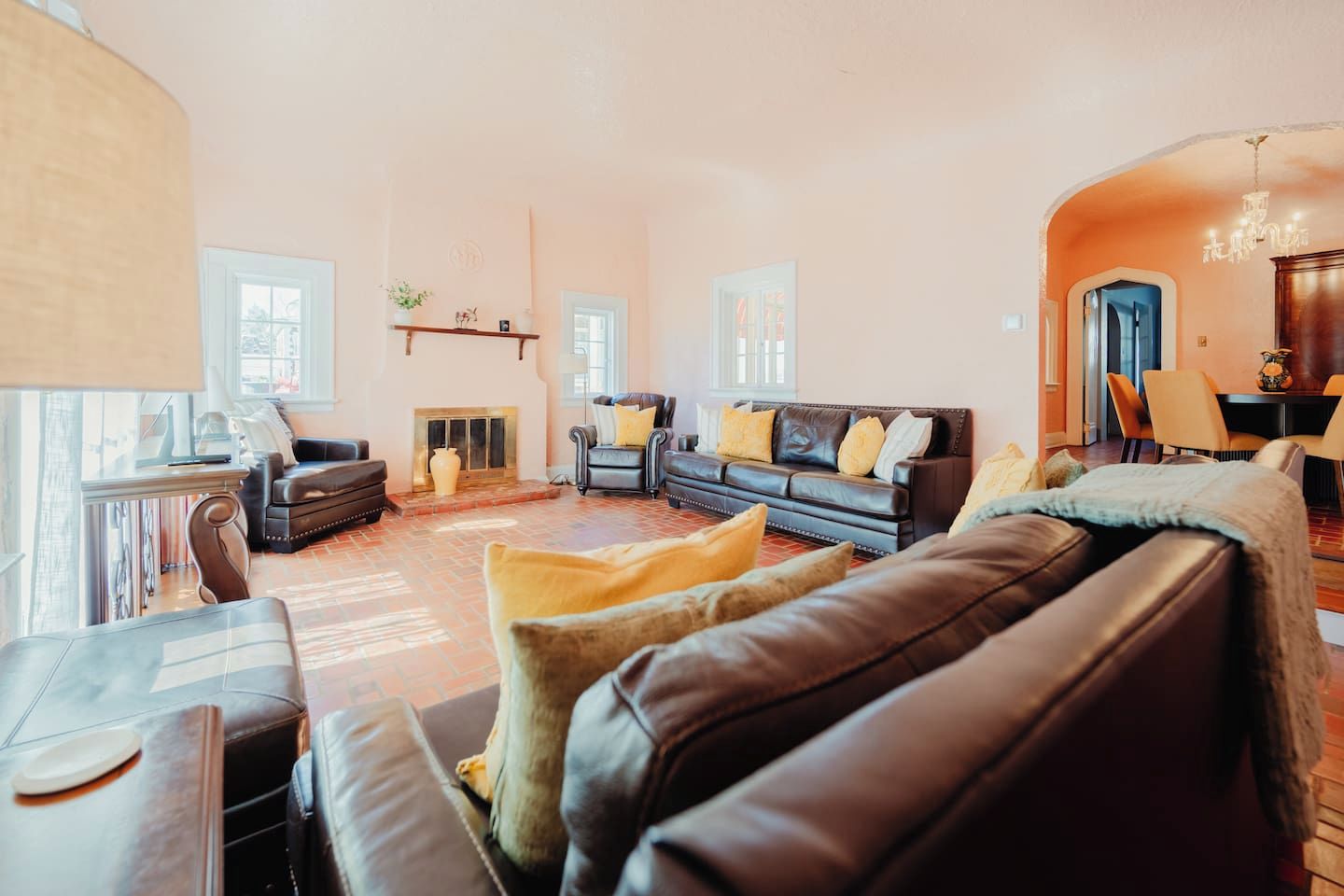 Ein geräumiges Wohnzimmer mit Ledersofas, einem Kamin und einem Essbereich mit Stühlen.