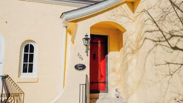 Un edificio con una puerta roja, una ventana pequeña y una placa con un número.