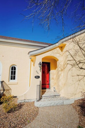 A building with a red door, a small window, and a number plaque.