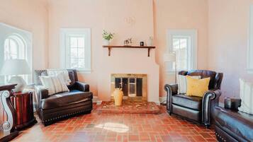 A living room with two leather sofas, a fireplace, and a tiled floor.