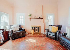 A living room with two leather sofas, a fireplace, and a tiled floor.