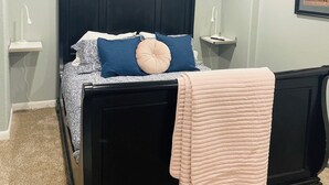 A bedroom with a black bed, a white bedside table, a nightstand, a framed picture on the wall, and a ceiling light. - Cozy 3-bedroom house in charming Casper with AC, WiFi. Centrally located!  (Casper)