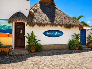 A building with a thatched roof, a blue door, and a sign reading 'Marea Azul'.