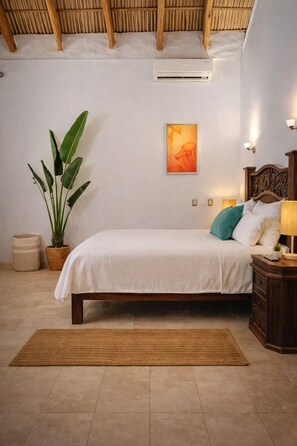 Ein Schlafzimmer mit einem Bett, einer Zimmerpflanze, einer Wandklimaanlage, einem gerahmten Bild und einem Nachttisch mit einer Lampe.