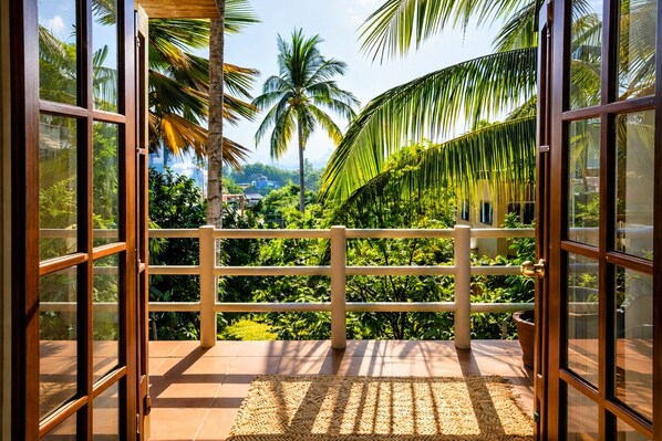 A balcony with a view of lush greenery and palm trees.