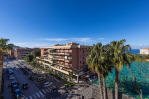 A multi-story hotel with balconies, a parking lot, and a view of the ocean.