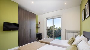 A modern hotel room with two beds, a TV mounted on the wall, a desk, and a view of the outdoors. - Amazing Home with terrace & view Sorrento Center (Sorrento)