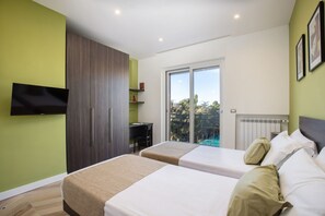 A modern hotel room with two beds, a TV mounted on the wall, a desk, and a view of the outdoors.