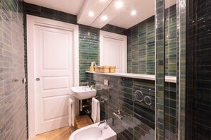 Un baño con lavamanos blanco, espejo y ducha.