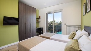 Une chambre d’hôtel moderne avec deux lits, un téléviseur fixé au mur, un bureau et une vue sur l’extérieur.
