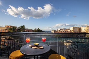 Un balcon avec une table, deux chaises et deux boissons.