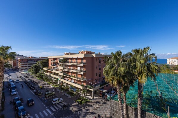 Un hotel a più piani con balconi, un parcheggio e vista sull'oceano.